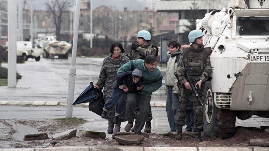 The residents of Sarajevo take cover from sniper fire behind a United Nations Protection Force (UNPROFOR) armoured vehicle in this 1993 file photo. Genocide, siege and massacre are for many people in Bosnia more than just words on Radovan Karadzic's indictment. They represent years of suffering, dead friends and nightmares that will always haunt them.    To match feature WARCRIMES-KARADZIC/LEGACY  REUTERS/Danilo Krstanovic/Files  (BOSNIA AND HERZEGOVINA) - RTR20HI6