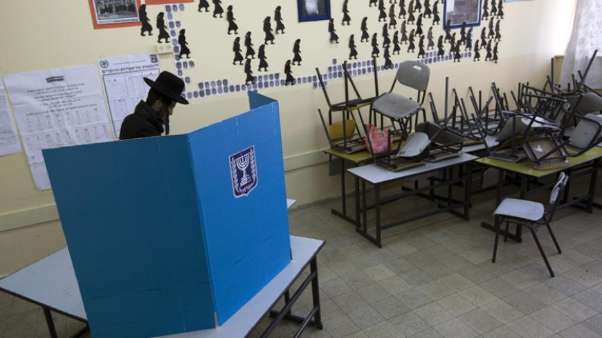 An ultra-Orthodox Jewish man stands behind a booth as he votes in the parliamentary election at a polling station in Jerusalem January 22, 2013. Israelis voted on Tuesday in an election that is expected to see Prime Minister Benjamin Netanyahu win a third term in office, pushing the Jewish state further to the right, away from peace with the Palestinians and towards a showdown with Iran. REUTERS/Ronen Zvulun (JERUSALEM - Tags: POLITICS ELECTIONS) - RTR3CSDF