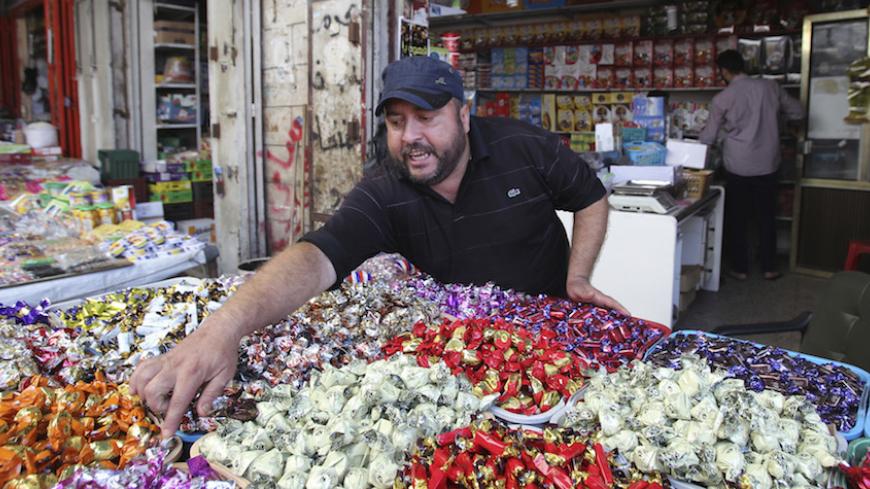 A Palestinian vendor sells sweets at a market in Gaza City July 26, 2014. Palestinians in the Gaza Strip poured into the streets on Saturday to recover their dead and stock up on food supplies after a 12-hour humanitarian truce agreed by Israel and Hamas took hold. Israel's military pledged to hold fire for 12 hours from 8 a.m. (0500 GMT) but press on searching for tunnels used by militants. The Islamist group Hamas, which dominates Gaza, said all Palestinian factions would abide by the brief truce. REUTERS