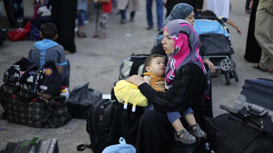 A Palestinian woman, hoping to cross into Egypt, holds her son as they wait with others at the Rafah crossing between Egypt and the southern Gaza Strip August 12, 2014. Under Egyptian President Abdel Fattah al-Sisi, Cairo has secured closures on the Gaza border, increasing economic pressure on Hamas from a long-running Israeli blockade. Talks to end a month-long war between Israel and Islamist militants in Gaza have made no progress so far, an Israeli official said on Tuesday, as a 72-hour ceasefire in the 