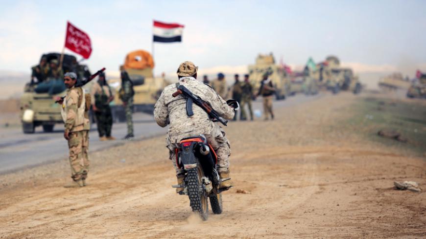 A Shi'ite fighter rides a motorbike in the town of Hamrin in Salahuddin province March 5, 2015. As Iraqi forces close in, Tikrit's few remaining civilians are cutting up white clothes and fabric to make flags of surrender, fearing their Shi'ite liberators more than the Islamic State militants occupying the Sunni city.  REUTERS/Stringer (IRAQ - Tags: POLITICS CIVIL UNREST CONFLICT) - RTR4S8Q5