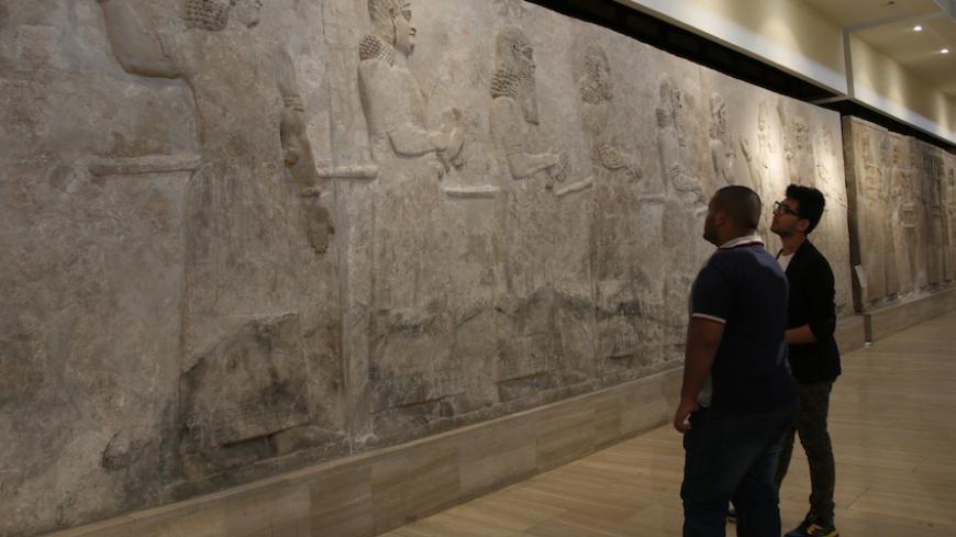 Visitors look at Assyrian mural sculptures from Khorsabad, at the Iraqi National Museum in Baghdad March 8, 2015. Islamic State militants have desecrated another ancient Iraqi capital, the government said on March 11, 2015, razing parts of the 2,700-year-old city of Khorsabad famed for its colossal statues of human-headed winged bulls.  Picture taken March 8, 2015.   REUTERS/Khalid al-Mousily (IRAQ - Tags: SOCIETY CIVIL UNREST) - RTR4SZAO