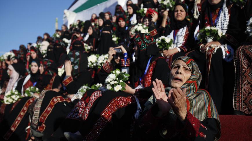 A Palestinian woman celebrates beside brides during a mass wedding for 250 couples in Rafah, in the southern Gaza Strip December 19, 2012. REUTERS/Ibraheem Abu Mustafa (GAZA - Tags: SOCIETY) - RTR3BR3Y