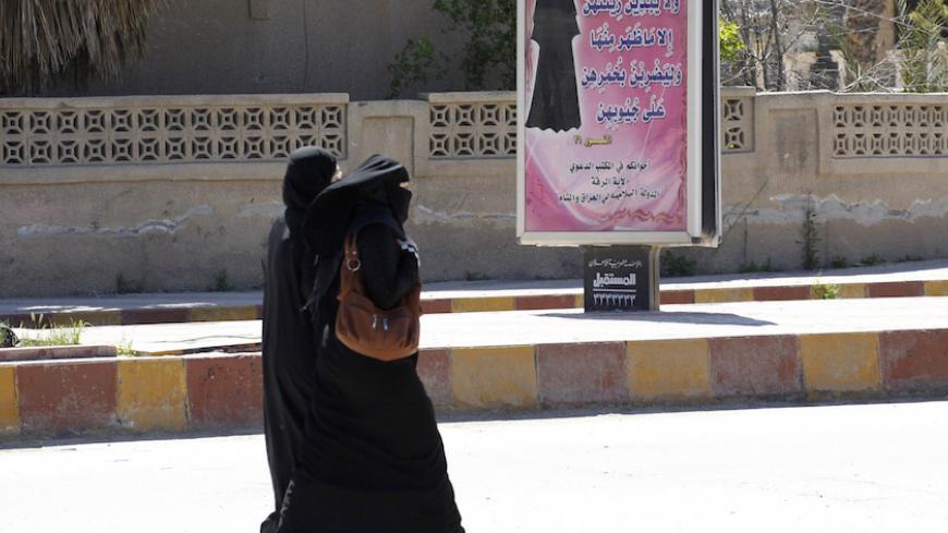 Veiled women walk past a billboard that carries a verse from Koran urging women to wear a hijab in the northern province of Raqqa March 31, 2014. The Islamic State in Iraq and the Levant (ISIL) has imposed sweeping restrictions on personal freedoms in the northern province of Raqqa. Among the restrictions, Women must wear the niqab, or full face veil, in public or face unspecified punishments "in accordance with sharia", or Islamic law. REUTERS/Stringer   (SYRIA - Tags: POLITICS CIVIL UNREST CONFLICT RELIGI