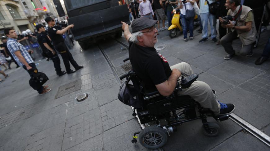 A demonstrator on a wheelchair blocks an armoured police vehicle on Istiklal Street in central Istanbul July 13, 2013. Turkish police fired water cannon and tear gas on Saturday to disperse hundreds of protesters who gathered to march to Gezi Park, which has been at the heart of fierce unrest against Prime Minister Erdogan's rule. Protesters scattered, running into sidestreets where police pursued them, before starting to regroup on Istiklal Street, metres from the main Taksim Square. REUTERS/Umit Bektas (T