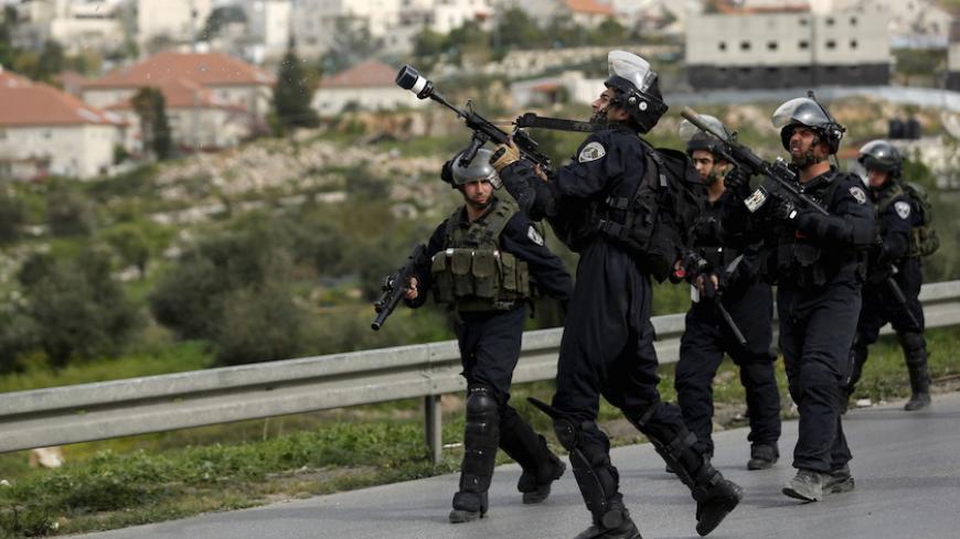 An Israeli border policeman fires a tear gas canister towards Palestinian stone-throwers as an Israeli settlement is seen in the background during clashes at a protest against Jewish settlements, in Jalazoun refugee camp near the West Bank city of Ramallah March 27, 2015. 
REUTERS/Mohamad Torokman  - RTR4V6AH