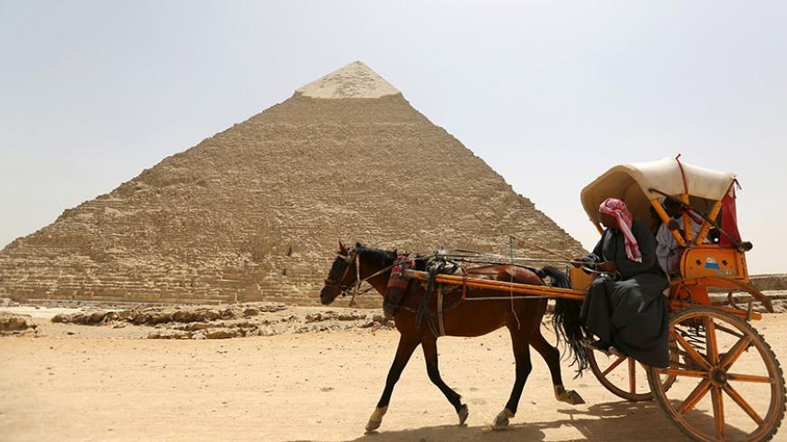 Arab tourists ride a horse cart at the Giza pyramid, on the outskirts of Cairo, April 27, 2015. Local media reported Egypt's Minister of Antiquities Mamdouh al-Damaty attended the opening of two tombs that were under rennovation on Monday. One tomb belongs to the Priest of King Khufu while the other belongs to his eldest son.  REUTERS/Mohamed Abd El Ghany - RTX1AHLY