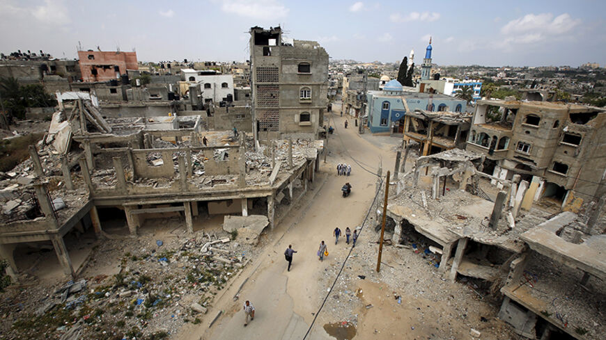 Palestinians walk past the ruins of houses that witnesses said were destroyed by Israeli shelling during a 50-day war last summer in Beit Hanoun in the northern Gaza Strip, where Palestinian boy al-Hassan, who was born in January 2014 after being conceived with his jailed father's sperm smuggled out of an Israeli prison, lives May 10, 2015. Hana, the Gaza wife of al-Za'an, a Palestinian prisoner in an Israeli jail, gave birth to a baby boy in January 2014 in the first successful smuggling of sperm to lead t