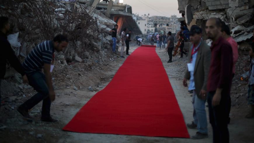 Palestinians place a red carpet between the ruins of houses, that witnesses said were destroyed by Israeli shelling during a 50-day war last summer, before they display a film on the war in the east of Gaza City May 12, 2015. REUTERS/Mohammed Salem 







 - RTX1CNQ9
