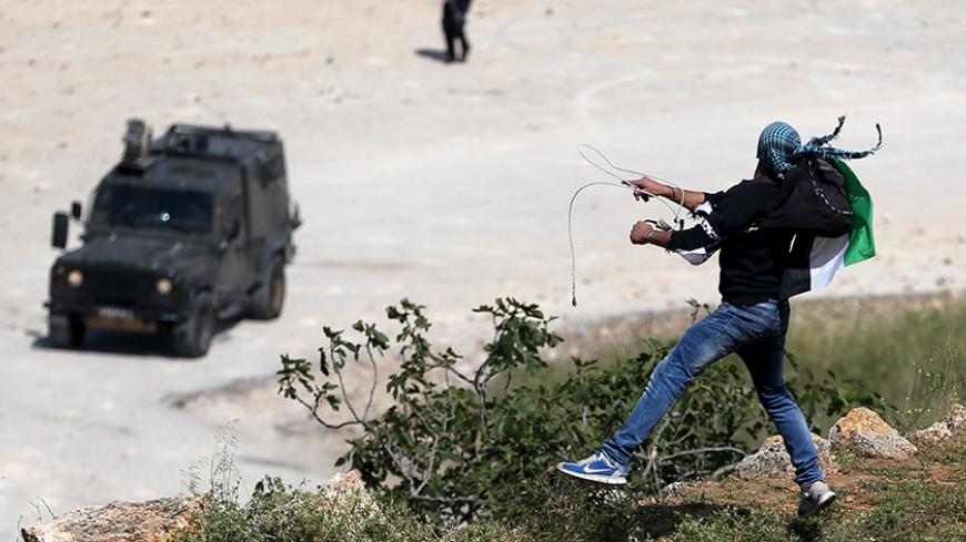 A Palestinian protester throws a stone towards Israeli troops during clashes following a rally marking Nakba Day near Israel's Ofer Prison near the West Bank city of Ramallah May 15, 2015. Palestinians mark "Nakba" (Catastrophe) on Friday to commemorate the expulsion or fleeing of some 700,000 Palestinians from their homes in the war that led to the founding of Israel in 1948. REUTERS/Mohamad Torokman
 - RTX1D4RJ