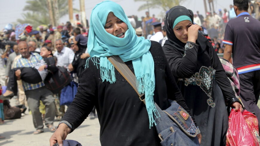 Displaced Sunni women fleeing the violence in Ramadi, carry bags as they walk on the outskirts of Baghdad, May 24, 2015. Iraqi forces recaptured territory from advancing Islamic State militants near the recently-fallen city of Ramadi on Sunday, while in Syria the government said the Islamists had killed hundreds of people since capturing the town of Palmyra.  REUTERS/Stringer - RTX1ED8I