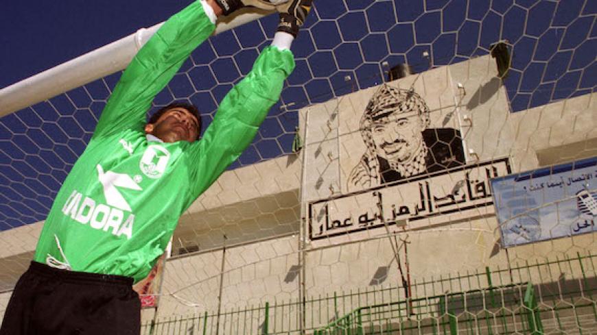A Palestinian goalkeeper practices fielding shots in a file photo at the Gaza football stadium where a large mural of Palestinian President Yasser Arafat hangs behind the goal. The Palestinian national football team is now playing in its first international tournament in Hong Kong in the Asian Group 3 qualifying competition for next year's World Cup finals. The team returns to the Middle East for its next World Cup qualifier on March 20 when it plays in Qatar.

EH - RTR13FBT