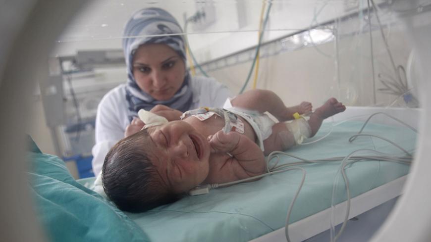 A Palestinian nurse tends to a baby inside an incubator in a hospital in Khan Younis in the southern Gaza Strip March 24, 2012. Israel allowed nine fuel tankers to cross into the Gaza Strip on Friday to ease a severe power shortage triggered by a dispute over supplies between Egypt and the enclave's Hamas Islamist rulers. The fuel crisis has crippled Gaza in recent weeks. Petrol pumps have run dry and its 1.7 million residents are suffering major electricity blackouts.  REUTERS/ Ibraheem Abu Mustafa (GAZA -