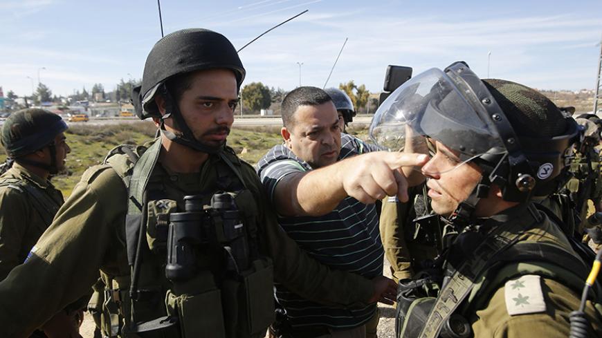 An Israeli settler argues with Israeli soldiers during a protest organised by Palestinians against Jewish settlements near the settlement bloc of Gush Etzion in the southern West Bank city of Bethlehem January 23, 2015. REUTERS/Mussa Qawasma (WEST BANK - Tags: POLITICS CIVIL UNREST MILITARY) - RTR4MMV0
