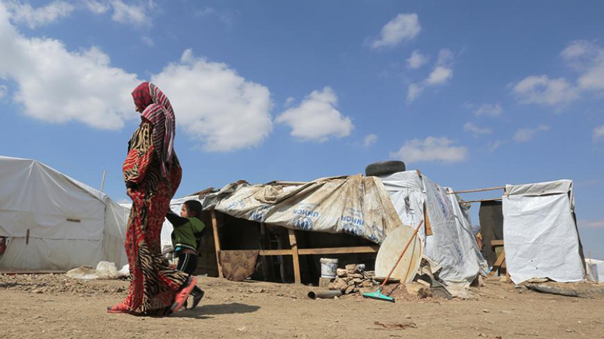 A woman and child walk at a makeshift settlement for Syrian refugees in Bar Elias, in the Bekaa valley, March 15, 2015. March 15 marks the fourth anniversary of peaceful protests against Syrian President Bashar al-Assad, leading to the devastating civil conflict in the country. Britain-based Syrian Observatory for Human Rights said more than 215,000 people have been killed since the start of the crisis in 2011, around half of them civilians. REUTERS/Jamal Saidi (LEBANON - Tags: CIVIL UNREST CONFLICT SOCIETY
