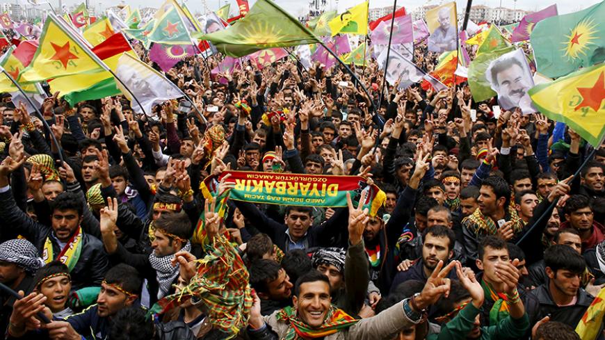 People gesture while others wave Kurdish flags during a gathering celebrating Newroz, which marks the arrival of spring and the new year, in Diyarbakir March 21, 2015. Jailed Kurdish rebel leader Abdullah Ocalan called on Saturday for his militant group to hold a congress on ending a three-decade insurgency against the Turkish state but stopped short of declaring an immediate halt to its armed struggle. Tens of thousands of Kurds gathered in the southeastern city of Diyarbakir to hear the message from Kurdi