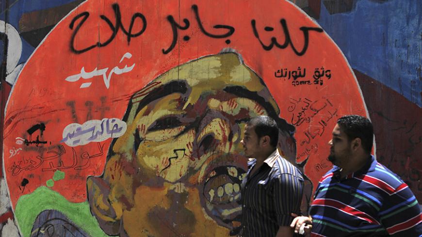 People walk in front of a graffiti of activist Khaled Said on the wall near Tahrir Square in downtown Cairo on the third anniversary of Said's death, June 6, 2013. Said, 28, was beaten to death by police in Alexandria in June 2010 with his body barely recognisable after he posted a video showing police officers sharing the spoils of a drugs bust, according to his family. The act of brutality galvanised further protests, in particular, the anti-torture Facebook page "We are Khaled Said". The page helped crys