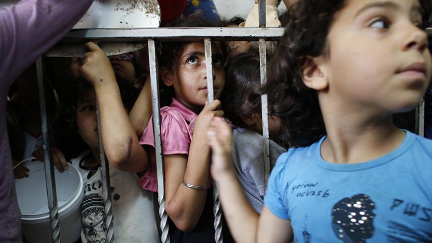 Palestinian children wait to receive food, donated by the Islamic endowment authority Islamic waqf, at a soup kitchen in the West Bank city of Hebron during the holy month of Ramadan July 18, 2013. During Ramadan there is an increase in demand for food, a manager at the soup kitchen said. REUTERS/Ammar Awad (WEST BANK - Tags: RELIGION FOOD SOCIETY) - RTX11QC5