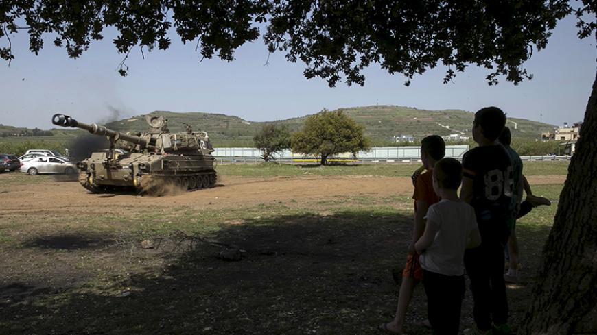 Druze children look at an Israeli army mobile artillery unit in Buqata in the Golan Heights April 27, 2015. An Israeli air strike killed four militants on Sunday as they placed an explosive on a fence near Israel's frontier with Syria in the annexed Golan Heights, an Israeli military source said. Tensions have risen in the Golan Heights, territory Israel captured from Syria in a 1967 war and later annexed in a move never recognised internationally, amid the civil war raging in Syria in the past four years. 
