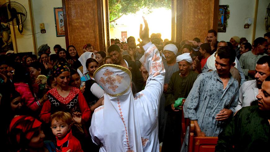 A Coptic Christian priest blesses his congregation with holy water during Sunday service in the Virgin Mary Church at Samalout Diocese in Al-Our village, in Minya governorate, south of Cairo, May 3, 2015. Copts have long complained of discrimination under successive Egyptian leaders and Sisi's actions suggested he would deliver on promises of being an inclusive president who could unite the country after years of political turmoil. However, striking out at extremists abroad might prove easier than reining i