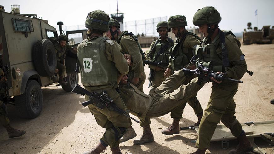 Israeli soldiers carry their comrade during a military exercise in the region bordering the Gaza Strip, southern Israel June 7, 2015. REUTERS/Amir Cohen - RTX1FI8P