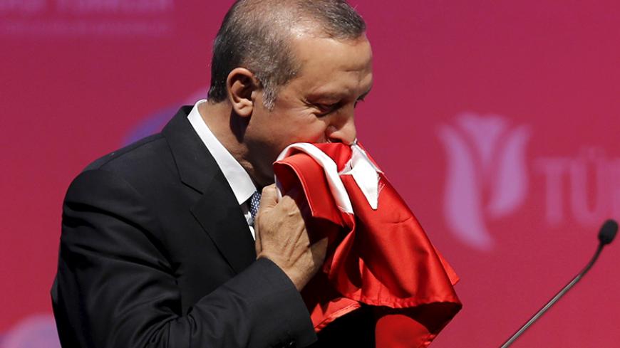 Turkey's President Tayyip Erdogan kisses a handmade Turkish flag, given to him as a gift from Ugandan university student Cemil (not pictured), during a graduation ceremony in Ankara, Turkey, June 11, 2015. REUTERS/Umit Bektas  - RTX1G1TU