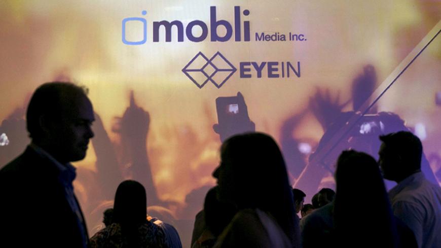 People are silhouetted in front of a screen depicting the logo of Israeli start-up, Mobli Media Inc, during their launch in Tel Aviv, Israel June 15, 2015. Israeli start-up Mobli Media Inc is taking on Internet giants Google, Facebook and Yahoo with an innovative online search tool to find the latest photos and videos across social media sites, the company said on Monday. REUTERS/Baz Ratner  - RTX1GMA5