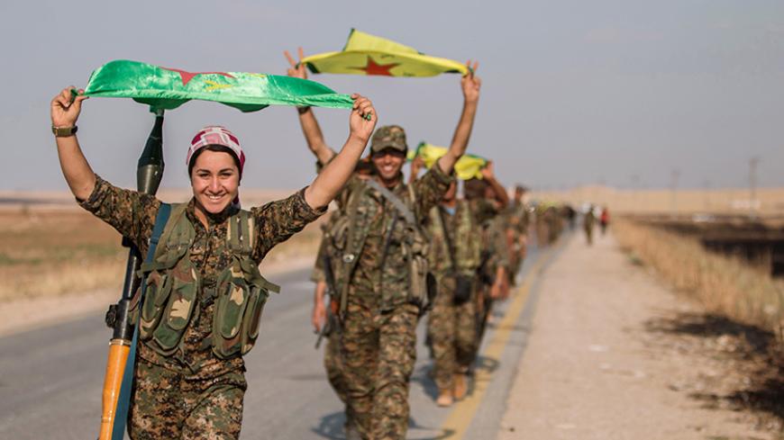 Kurdish fighters gesture while carrying their parties' flags in Tel Abyad of Raqqa governorate after they said they took control of the area June 15, 2015. Syrian Kurdish-led forces said they had captured a town at the Turkish border from Islamic State on Monday, driving it away from the frontier in an advance backed by U.S.-led air strikes that has thrust deep into the jihadists' Syria stronghold. The capture of Tel Abyad by the Kurdish YPG and smaller Syrian rebel groups means the Syrian Kurds effectively