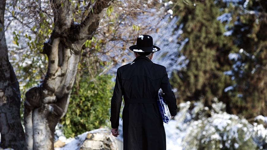 An Ultra-Orthodox Jewish man walks on a snow-covered street near Jerusalem's Old City January 10, 2015.  REUTERS/Ronen Zvulun (JERUSALEM - Tags: ENVIRONMENT RELIGION TPX IMAGES OF THE DAY) - RTR4KTNO