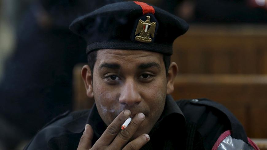 A policeman smokes cigarette after the trial of Muslim brotherhood leaders in Cairo, April 11, 2015. An Egyptian court sentenced Mohamed Badie, the leader of the outlawed Muslim Brotherhood, and 13 other senior members of the group to death for inciting chaos and violence, a judge said in a televised session on Saturday. REUTERS/Amr Abdallah Dalsh - RTR4WWAS