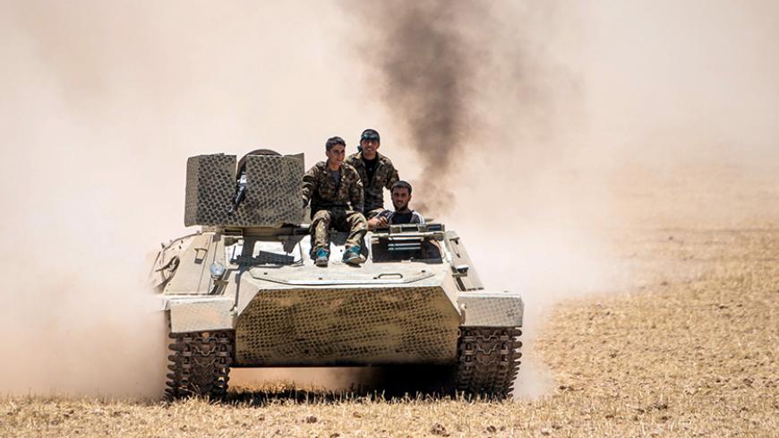 Kurdish People's Protection Units (YPG) fighters drive a tank at the eastern entrances to the town of Tal Abyad in the northern countryside of Raqqa, Syria, June 14, 2015, after they took control of nearby Suluk town from Islamic State fighters. The YPG, working with the U.S.-led alliance and small Syrian rebel groups, has pushed into Islamic State's Syrian stronghold of Raqqa province, threatening one of its supply lines to the jihadists' de facto capital, Raqqa city.  REUTERS/Rodi Said - RTX1GFQ8