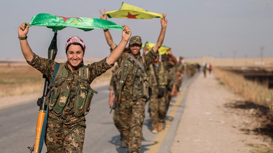 Kurdish fighters gesture while carrying their parties' flags in Tel Abyad of Raqqa governorate after they said they took control of the area June 15, 2015. Syrian Kurdish-led forces said they had captured a town at the Turkish border from Islamic State on Monday, driving it away from the frontier in an advance backed by U.S.-led air strikes that has thrust deep into the jihadists' Syria stronghold. The capture of Tel Abyad by the Kurdish YPG and smaller Syrian rebel groups means the Syrian Kurds effectively