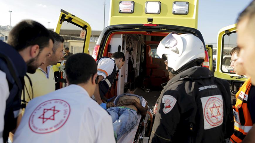 Israeli medics wheel a wounded Palestinian into an ambulance at Qalandiya checkpoint near the West Bank city of Ramallah June 30, 2015. On Tuesday Israeli guards opened fire on the man at a West Bank checkpoint, wounding him, after he ran at them shouting "God is great" in Arabic and ignored warning shots, a police spokesman said. REUTERS/Ammar Awad  - RTX1IGQ4