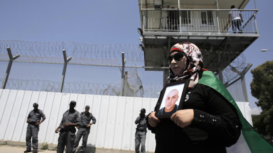 A Palestinian woman holds a picture of a Palestinian jailed in an Israeli prison during a protest calling for the prisoner's release outside the Ayalon prison, in the city of Ramle, near Tel Aviv May 23, 2014. REUTERS/Ammar Awad (ISRAEL - Tags: POLITICS CIVIL UNREST) - RTR3QJ6R