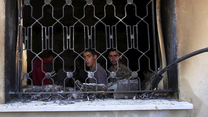 Palestinians look out of a house that had been torched in a suspected attack by Jewish extremists, killing an 18-month-old Palestinian child, injuring a four-year-old brother and both their parents at Kafr Duma village near the West Bank city of Nablus July 31, 2015. The house fire in the occupied West Bank suspected to have been set by Jewish extremists on Friday, Israeli security officials said. A neighbouring house was also badly damaged but it had been empty and there were no casualties there. The three