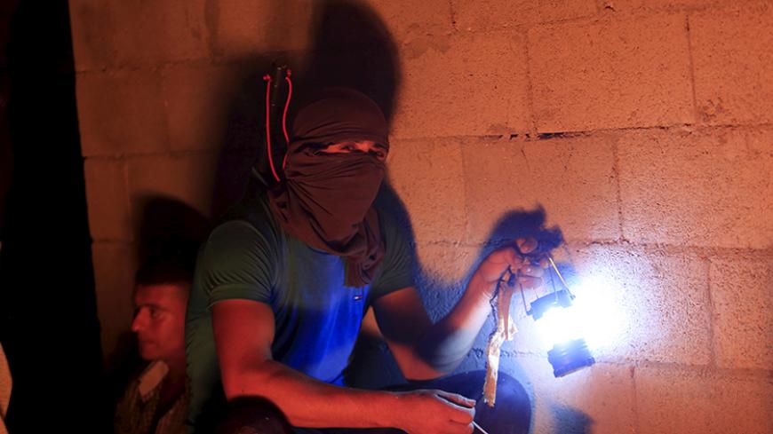 A masked Palestinian villager keeps guard with other Palestinians as they tighten night guards against Jewish settler threats, at Qusra village near the West Bank city of Nablus August 10, 2015. Fears of attacks by far-right Jews have increased since a Palestinian man and his 18-month-old son were killed when their house in Duma village was set ablaze on July 31, giving Palestinian farmers-turned-volunteer watchmen patrolling their own villages a renewed sense of urgency. Picture taken August 10, 2015. REUT