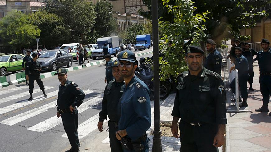 Police officers watch as a convoy carrying members of the British media leaves the British Embassy in Tehran, Iran August 23, 2015.  Britain reopened its embassy in Tehran on Sunday, nearly four years after protesters ransacked the ambassador's residence and burned the Union Jack. In a signal of the most striking thaw in Western ties with Iran for over a decade, Foreign Secretary Philip Hammond watched the British flag being raised in the garden of the opulent 19th century building while the national anthem