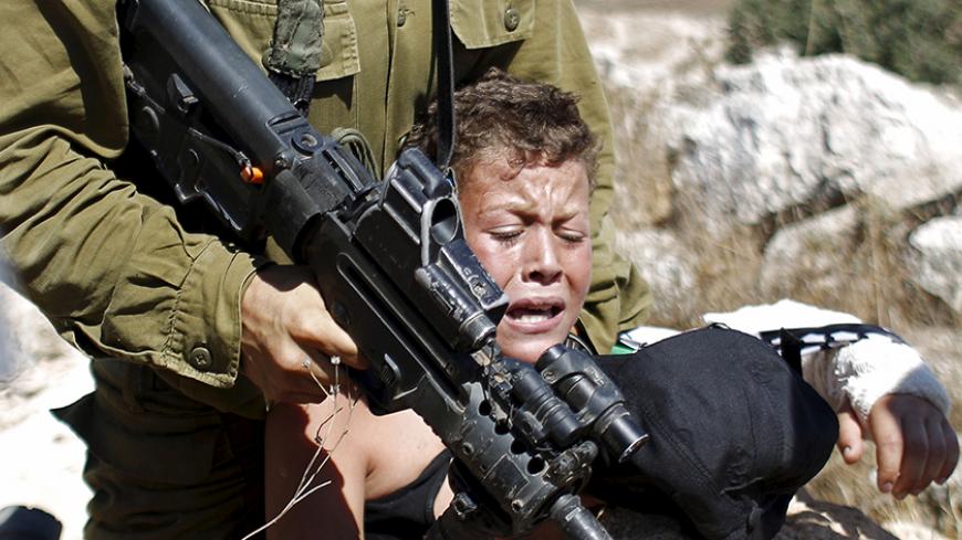 An Israeli soldier detains a Palestinian boy during a protest against Jewish settlements in the West Bank village of Nabi Saleh, near Ramallah August 28, 2015. REUTERS/Mohamad Torokman  - RTX1Q2I3