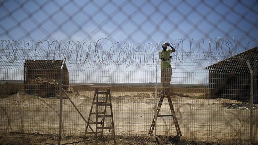 An Israeli worker repairs a fence damaged by a tank in Kibbutz Nahal Oz , just outside the northern Gaza Strip, September 3, 2014. Israelis living on the Gaza border have warily returned home after fleeing constant mortar and rocket fire during a seven-week war, feeling it is just a matter of time before their villages are targeted again. Picture taken September 3, 2014. REUTERS/Amir Cohen (ISRAEL - Tags: POLITICS TPX IMAGES OF THE DAY CONFLICT) - RTR44YGI