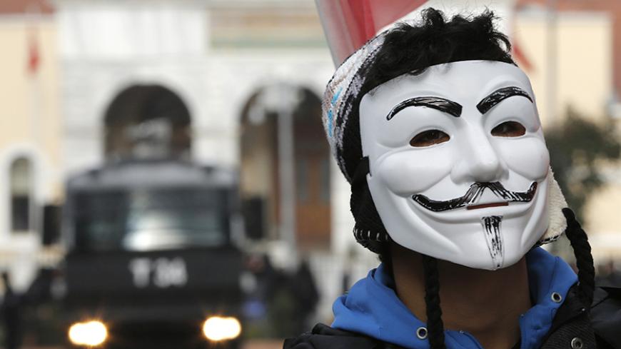 A high school student wearing a Guy Fawkes mask takes part in a protest against the education policies of the ruling AK Party, as a police vehicle is seen in the background, in Istanbul February 13, 2015. Education is the latest flashpoint between the administration of President Tayyip Erdogan, and secularist Turks who accuse him of overseeing creeping 'Islamisation' in the NATO member state. Parts of some regular schools have been requisitioned to create more places for students in "Imam Hatip" religious s