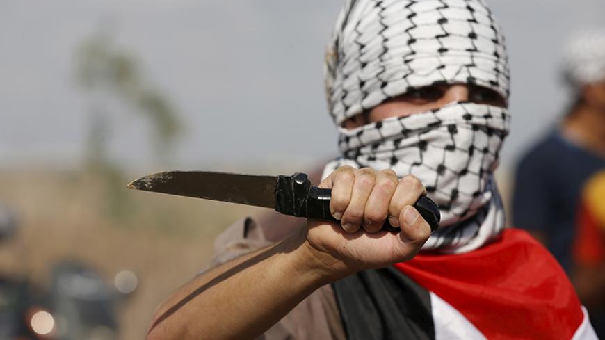 A masked Palestinian protester holds a knife during a protest near the Israeli border fence in northeast Gaza October 9, 2015. Israeli troops fired across the border into Gaza on Friday, killing four Palestinians and wounding at least a dozen others who were throwing stones during a rally in support of protests in Jerusalem, hospital officials in Gaza said. REUTERS/Mohammed Salem - RTS3QE4