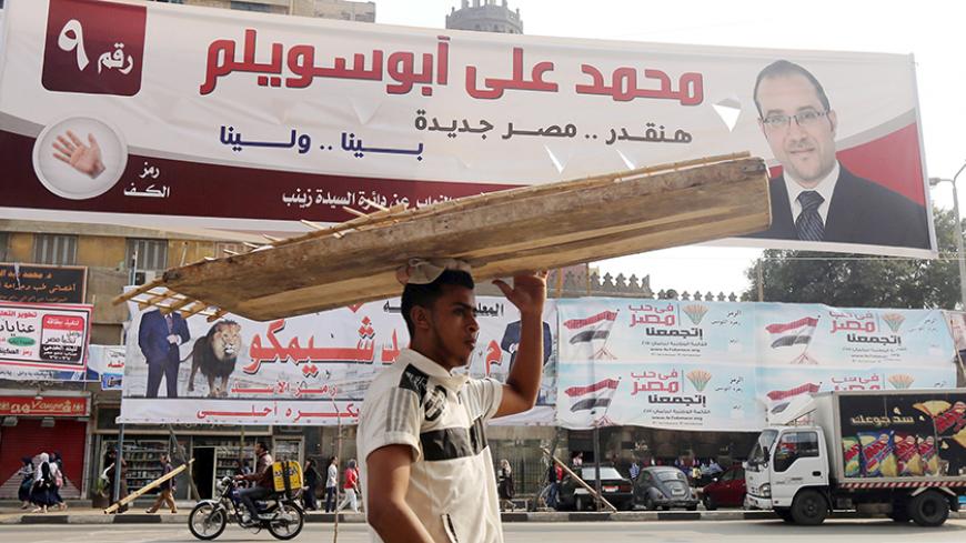 A street vendor walks under election campaign banners in downtown Cairo, ahead of the second round of parliamentary election, November 19, 2015. Official results showed a political alliance loyal to Egyptian President Abdel Fattah al-Sisi has scooped all 60 list seats up for grabs in the first round of a parliamentary election in which opposition parties were all but absent. REUTERS/Mohamed Abd El Ghany - RTS7XID