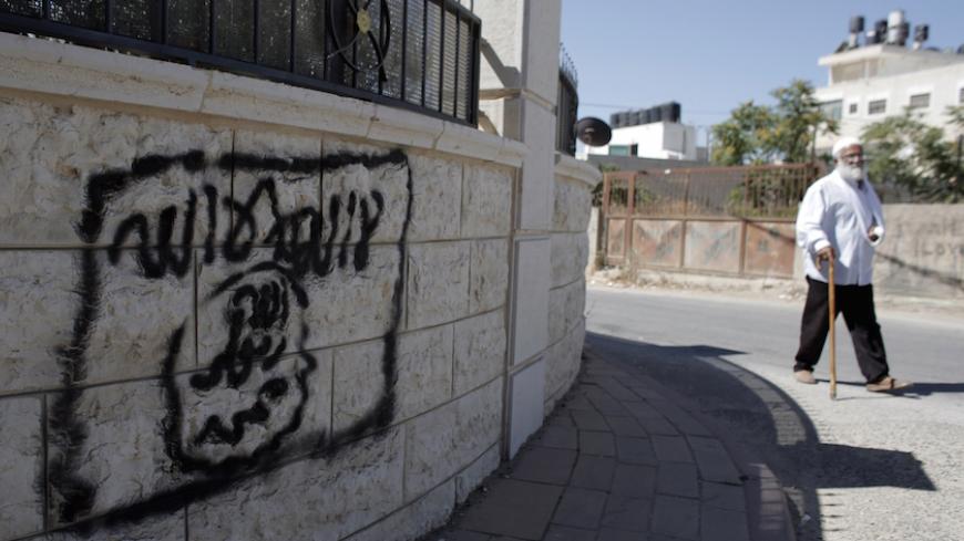 A Palestinian man walks past a graffiti portraying the Islamic State (IS) group's flag in the East Jerusalem neighbourhood of Beit Hanina on July 5, 2015. AFP PHOTO / AHMAD GHARABLI        (Photo credit should read AHMAD GHARABLI/AFP/Getty Images)