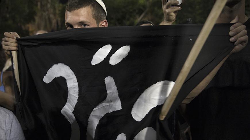 An Israeli right-wing activist holds a black flag with the Hebrew words for "High Court" during a rally to protest a recent court decision ordering Israel to release thousands of African migrants from detention, in Tel Aviv October 5, 2014. Israel's high court last month outlawed a detention centre where African migrants are held without trial and ordered some 2,000 inmates there released over the next three months. REUTERS/Finbarr O'Reilly (ISRAEL - Tags: POLITICS SOCIETY RELIGION CIVIL UNREST) - RTR490U7