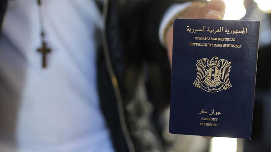 Christian Syrian refugee Ghassan Aleid displays his Syrian passport at a terminal at the Charles-de-Gaulle Airport in Roissy, France, October 2, 2015. After the efforts of the mayor of Le Mans and a family member, a doctor residing in Le Mans, France accorded travel visas, requested a year ago, for the family who fled the conflict in Syria.   REUTERS/Stephane Mahe - RTS2S8H