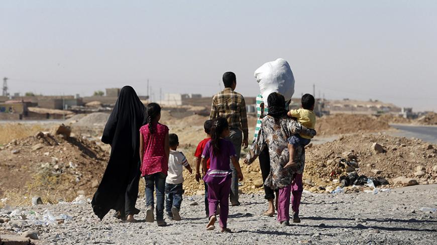 A displaced family from the minority Yazidi sect, fleeing the violence, walks towards the entrance of Mosul, in northern Iraq August 21, 2014. Iraqi and Kurdish forces recaptured Iraq's biggest dam from Islamist militants with the help of U.S. air strikes to secure a vital strategic objective in fighting that threatens to break up the country, Kurdish and U.S. officials said on Monday.  REUTERS/Youssef Boudlal (IRAQ - Tags: CIVIL UNREST POLITICS MILITARY CONFLICT) - RTR437XY