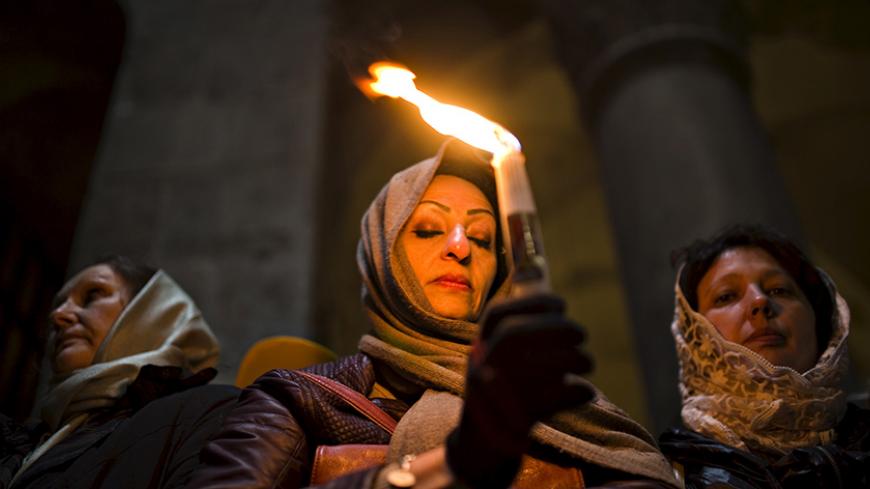 A Christian worshipper holds a candle, before Easter Sunday mass procession inside the Church of the Holy Sepulchre in Jerusalem's old city April 12, 2015. REUTERS/Amir Cohen - RTR4X06K