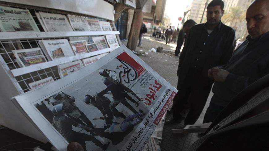 An Egyptian man looks at Al Tahrir newspaper featuring a front page picture of security forces beating a female demonstrator during Saturday's clashes near Tahrir Square in Cairo December 18, 2011. Protesters and troops fought in Cairo on Sunday, the third day of clashes that have killed 10 people and exposed rifts over the army's role as it manages Egypt's promised transition from military to civilian rule.   REUTERS/Amr Abdallah Dalsh  (EGYPT - Tags: CIVIL UNREST POLITICS MILITARY MEDIA) - RTR2VEGE