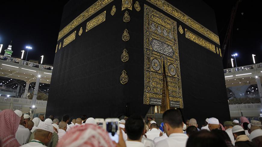 A Saudi policeman (R) stands watch as muslims touch and pray at the door of the Kaaba and touch and kiss the al-Hajr al-Aswad "Black Stone" during their Umrah Mawlid al-Nabawi "Birthday of Prophet Mohammad" in the holy city of Mecca, Saudi Arabia January 18, 2016. Picture taken January 18, 2016. REUTERS/Amr Abdallah Dalsh - RTX25AB8