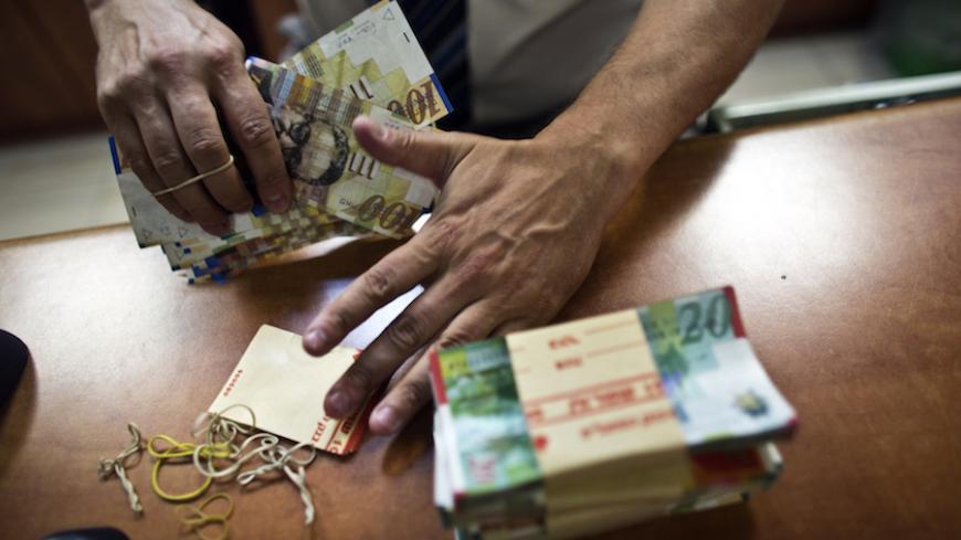 A bank employee counts Israeli Shekel notes for the camera at a bank branch in Tel Aviv August 7, 2013. Picture taken August 7, 2013. REUTERS/Nir Elias (ISRAEL - Tags: BUSINESS) - RTX12EW2